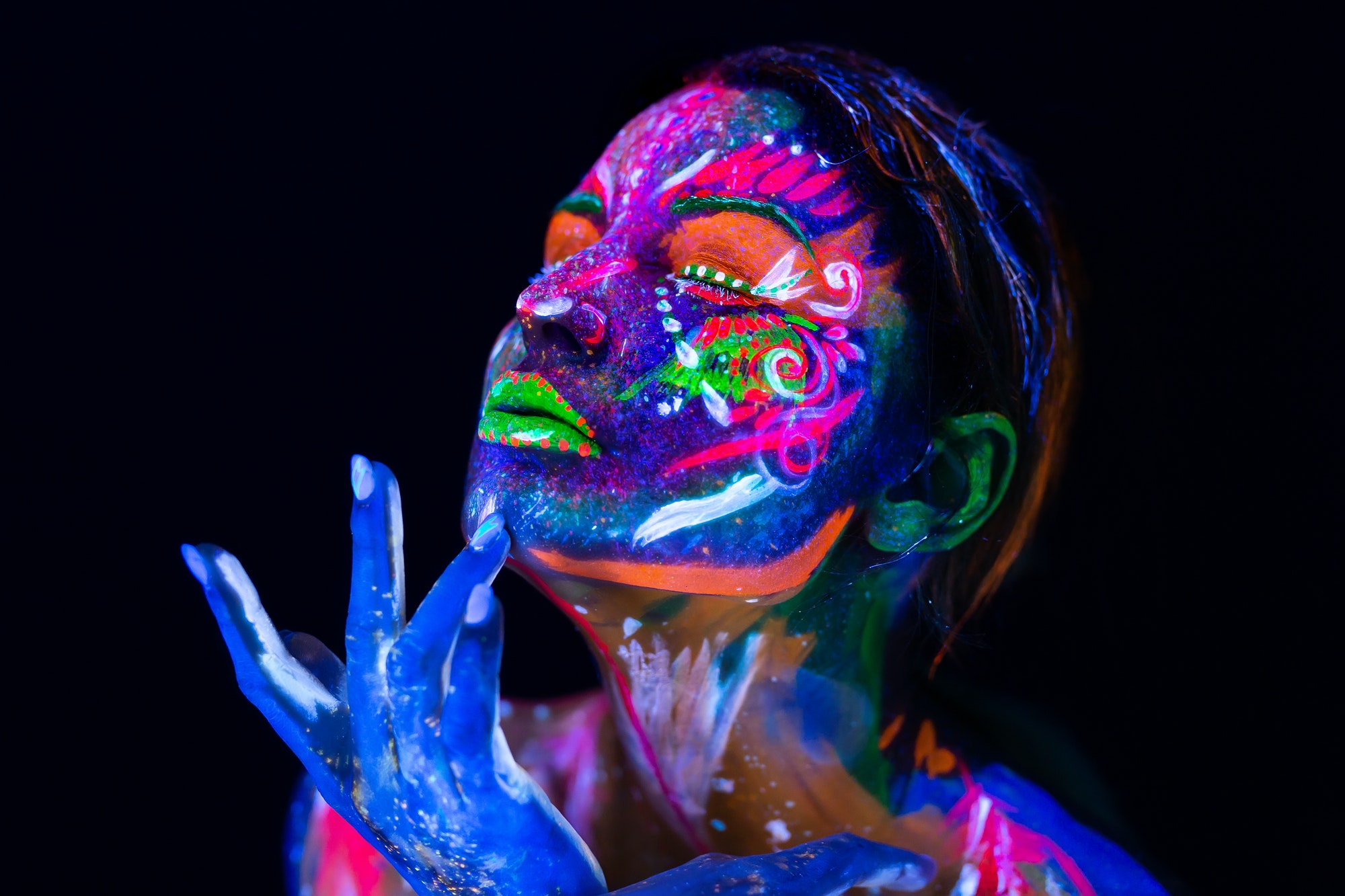 Body art glowing in ultraviolet light. Body art on the body and hand of a girl glowing in the